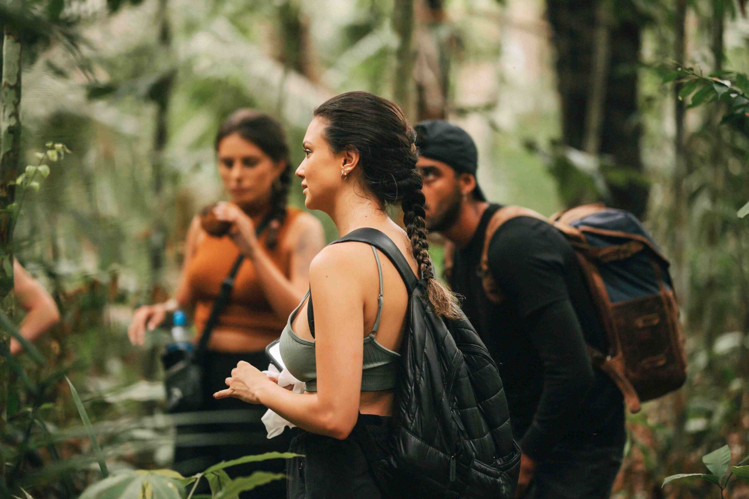 na foto há turistas durante a caminhada na selva, enquanto o guia explica sobre técnicas de sobrevivência na selva
